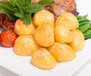 Golden roasted potatoes with grilled meat and vegetables plate