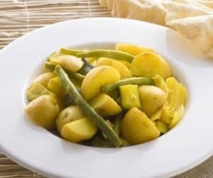 Plate of cooked potatoes with green beans and onions