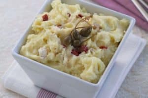 Mashed potatoes with bacon bits served in white bowl