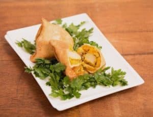 Samosa stuffed with egg and vegetables on white plate