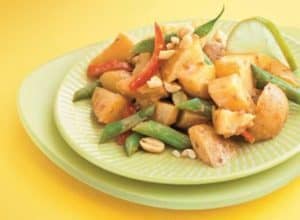 Plate of mixed vegetable and peanut salad on yellow background