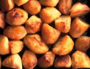 Roasted golden-brown potato wedges close-up texture background