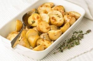 Roasted golden baby potatoes in white ceramic dish with thyme