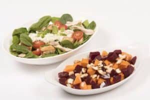 Two bowls of fresh vegetable salads with nuts and greens