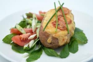 Baked loaded potato with melted cheese and fresh salad.