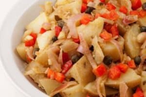 Bowl of cooked potatoes with diced red peppers and onions