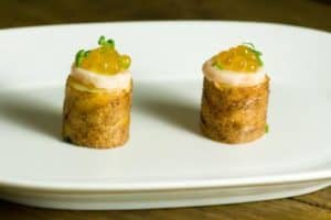 Two gourmet appetizers topped with sauce and garnish