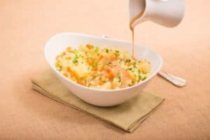 Creamy vegetable mashed potatoes with gravy being poured.