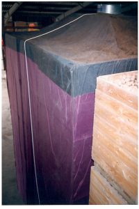 Large industrial storage bin covered with protective tarp indoors