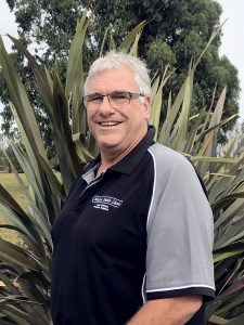 Smiling man wearing glasses and black-gray polo outdoors
