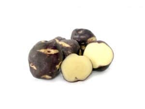 Purple Peruvian potatoes whole and sliced on white background