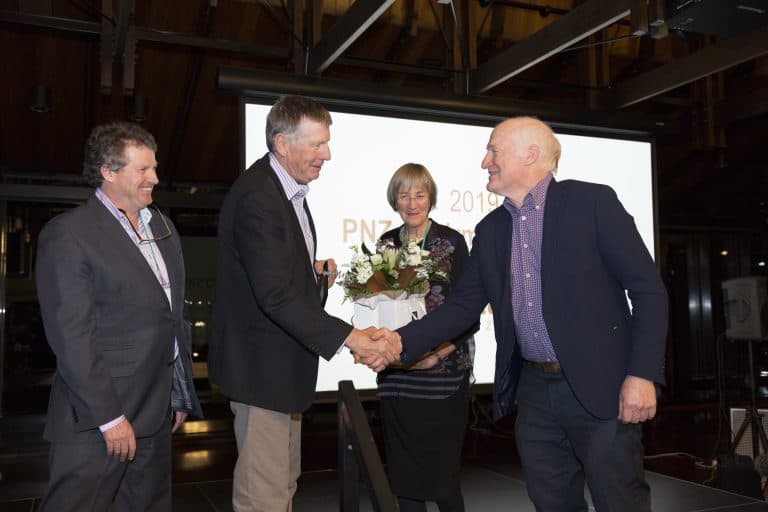 Men shaking hands and woman holding flowers at award event