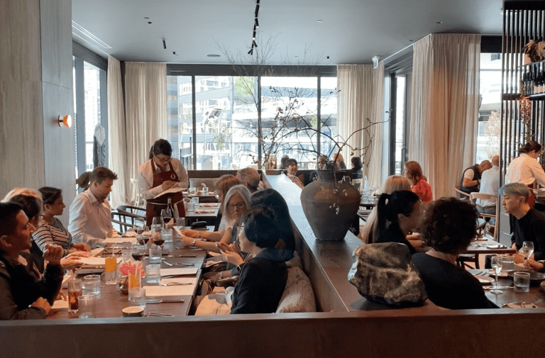 Busy modern restaurant interior with guests and waitstaff serving tables