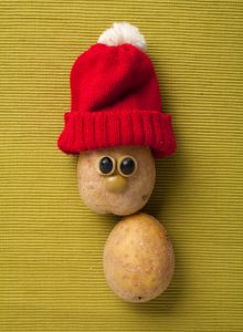 Happy Christmas potato in santa hat on yellow background
