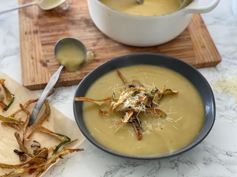 Creamy soup with vegetable chips and grated cheese garnish