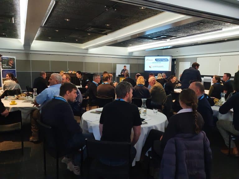 Business conference attendees seated at round tables listening to speaker