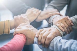 Dramatic moment. A group people hold strong hands. Sign of trust and teamwork. Corporate meeting concept.