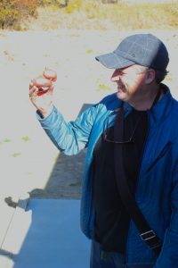 Man in blue jacket and cap holding a small clay pot outdoors