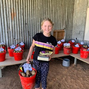 Girl holding a red bucket of potatoes at agricultural event