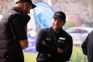 Two men smiling and talking, wearing HortCentre Charitable Trust uniforms.