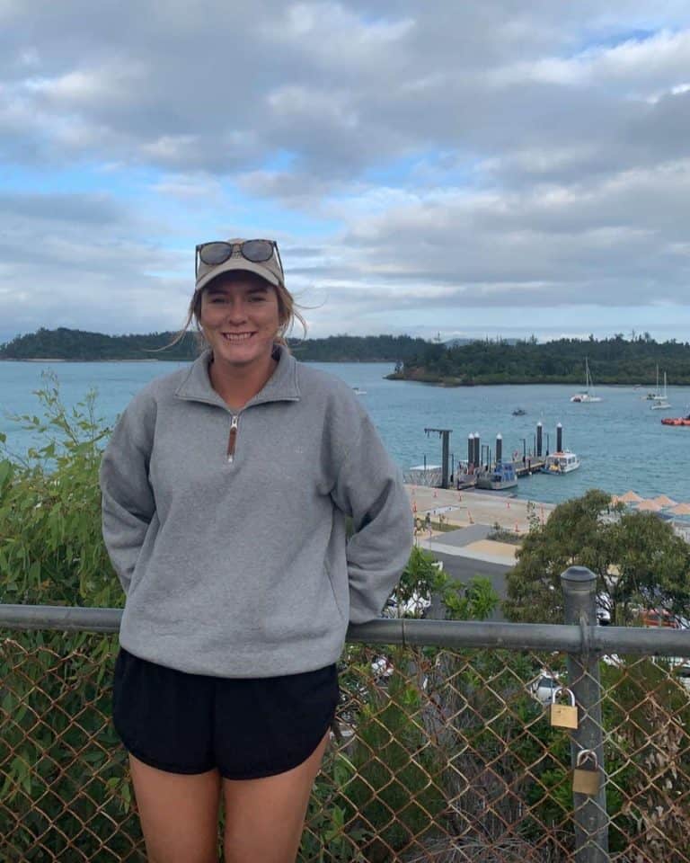 Young woman in casual wear smiling by waterfront with boats
