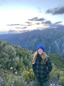 Woman wearing blue beanie and checkered jacket in mountain landscape