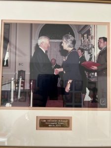 Formal handshake between elderly man and woman at government event
