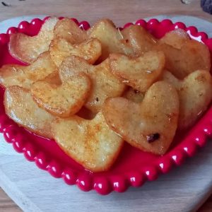 Heart-shaped fried potato slices on red heart-shaped plate