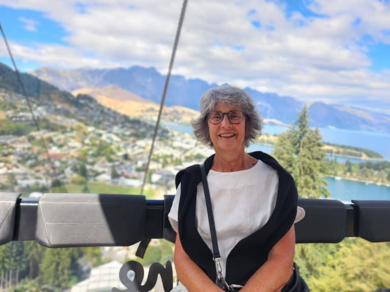 Smiling elderly woman on cable car with mountain landscape background
