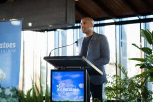 Man speaking at podium with Potatoes New Zealand logo and plants.