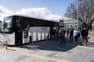 People boarding white Pacific Tourways coach bus in urban area