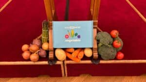 Box with "Add One More Vegetable" text surrounded by fresh vegetables