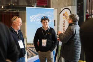 Three men conversing at Potatoes New Zealand event booth