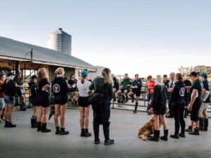 Group of people standing in circle outdoors on farm with dog