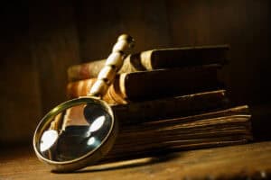 Vintage magnifying glass with antique books. Concept for learn history, investigation, find artifacts.