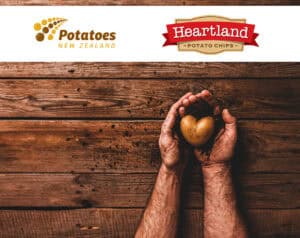 Natural heart shape potato and soil in farmerâs hands on wooden background