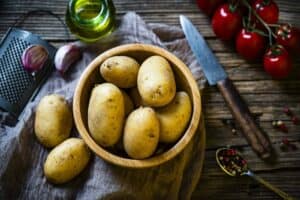 Bowl filled with raw fingerling potatoes shot from above on rustic table.