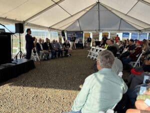 Outdoor business seminar with speaker and seated audience under tent