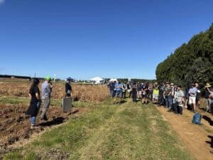 Group of people attending outdoor agricultural field presentation