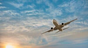 Commercial airplane flying in sky during sunset with clouds